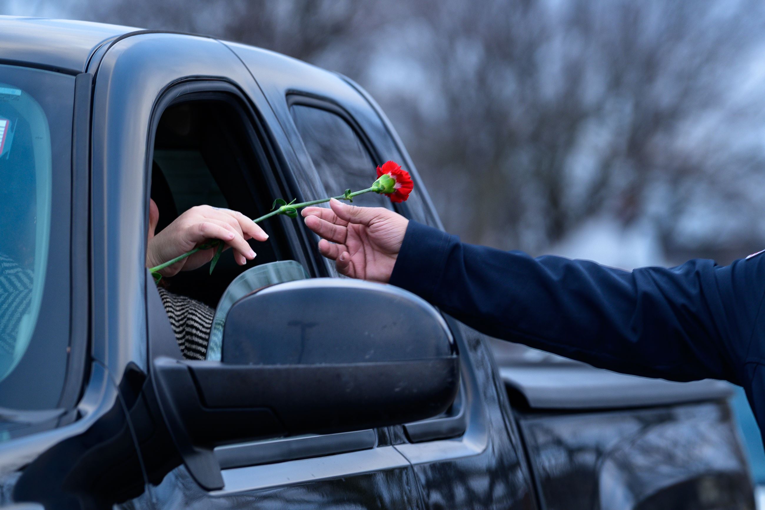 Officer handing parent a flower through car window